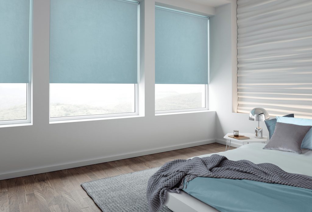 Image showing light blue blackout roller blinds in a light coloured bedroom
