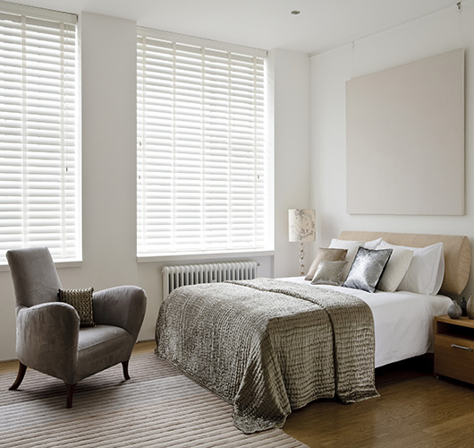 A white venetian blind opened in a bright and airy bedroom